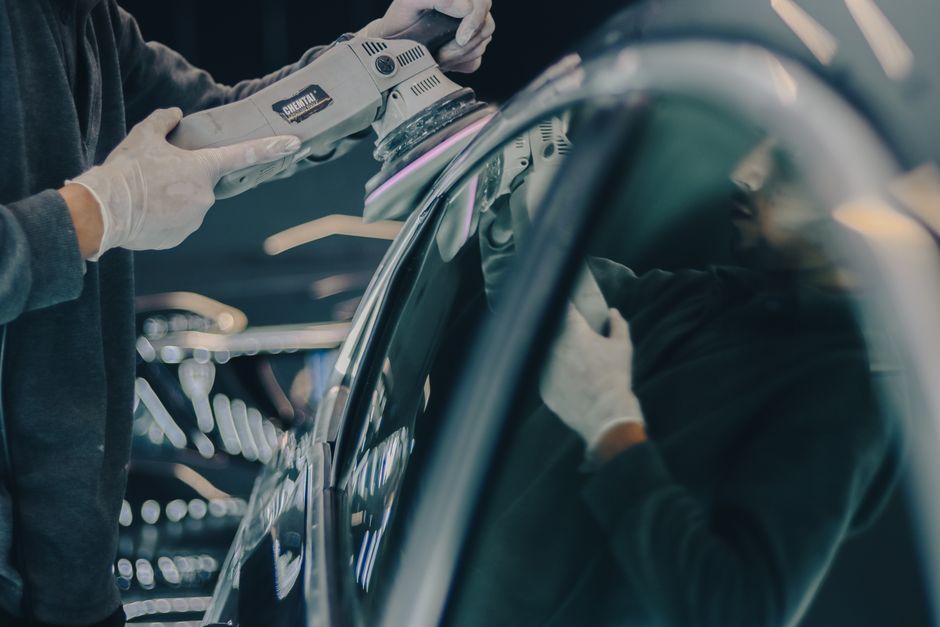 Professional auto detailer carefully inspecting a polished car